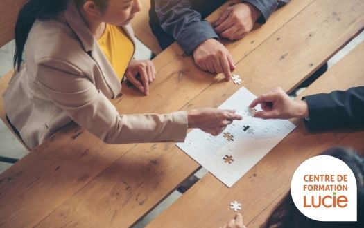 Photo de salariés qui joues au puzzle ensemble sur une table en bois